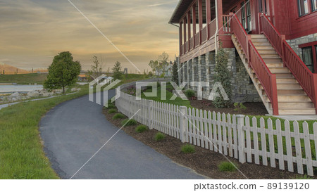 Panorama Whispy white clouds Curved asphalt pathway at the front of a fenced house at Daybrea 89139120
