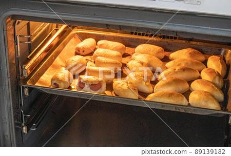 The concept of cooking homemade food, freshly baked hot pies with filling on a baking sheet in the oven The concept of cooking homemade food, freshly baked hot pies with filling on a baking sheet in the oven 89139182