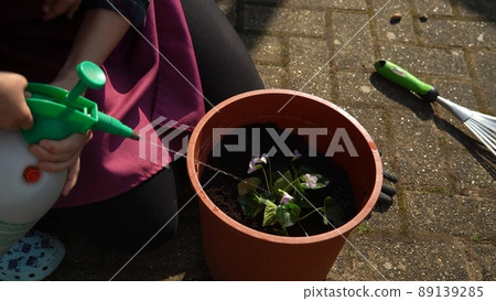 Happy Preschool little girl kid Daughter wear works gloves humic boots planting flowers in pot in garden. Child Helping mother outside. Family Nature gardering, environmental Spring Summer concept Happy Preschool little girl kid Daughter wear works gloves humic boots planting flowers in pot in garden. Child Helping mother outside. Family Nature gardering, environmental Spring Summer concept 89139285
