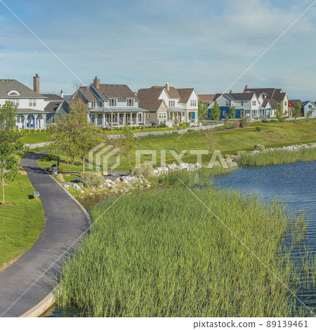 Square Whispy white clouds Oquirrh Lake at Daybreak in Utah with paved sidewalk on the side 89139461