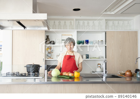 A beautiful woman in her 50s standing in the kitchen A beautiful woman in her 50s standing in the kitchen 89140146