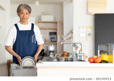 A man washing dishes in the kitchen A man washing dishes in the kitchen 89140453