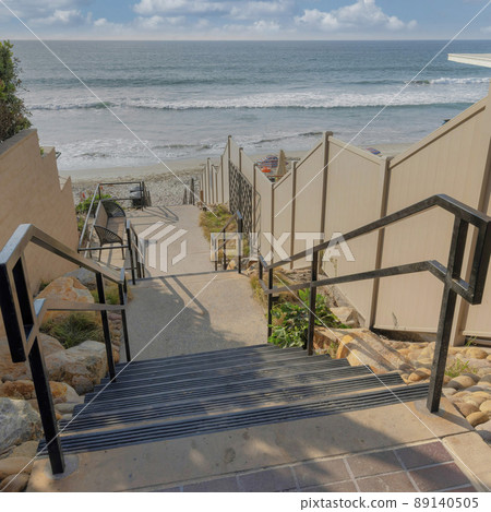Square White puffy clouds Staircase in the middle of beach houses' beige fences at Carlsba 89140505
