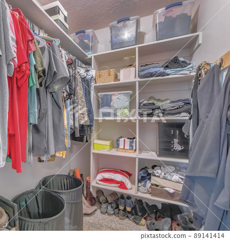 Square Small messy walk-in closet with a lot of shoes on the carpet floor 89141414