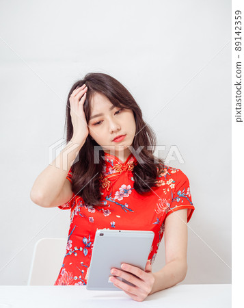 Beautiful asian woman wearing traditional cheongsam qipao dress suffering from headache desperate after using tablet on white background. Beautiful asian woman wearing traditional cheongsam qipao dress suffering from headache desperate after using tablet on white background. 89142359