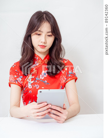Asian young woman wearing traditional cheongsam qipao dress using digital tablet online, e-commerce concept isolated on white background. 89142360