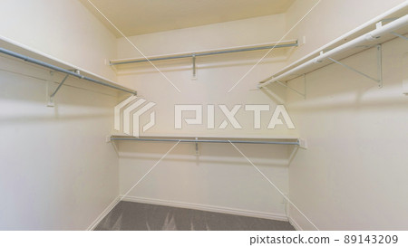 Panorama Empty walk in closet with gray carpet flooring and shelving unit 89143209