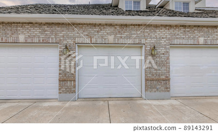 Panorama Puffy clouds at sunset Garage exterior with bricks and three white sectional doors Panorama Puffy clouds at sunset Garage exterior with bricks and three white sectional doors 89143291