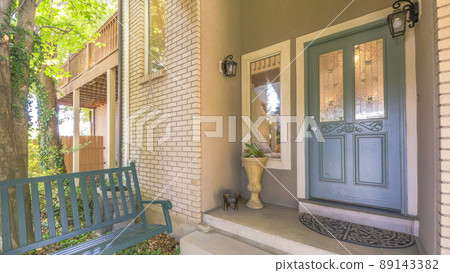 Panorama Gray front door with ornate glass panel near the picture window and wall lamps Panorama Gray front door with ornate glass panel near the picture window and wall lamps 89143382
