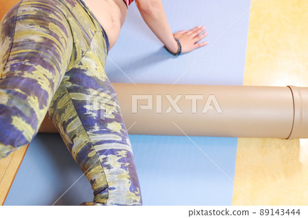 A woman exercising with a stretch pole. Loosen, stretch and train your body. A woman exercising with a stretch pole. Loosen, stretch and train your body. 89143444