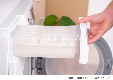 A man takes out container from the dryer to A man takes out container from the dryer to 89143492