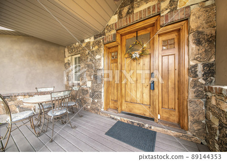 House entrance with chairs and table near the wooden front door 89144353
