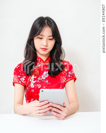 Written by a traditional flag, a smiling cheongsam, a female with a white background, used in front of a flat plate computer. Written by a traditional flag, a smiling cheongsam, a female with a white background, used in front of a flat plate computer. 89144907
