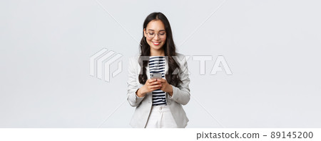 Business, finance and employment, female successful entrepreneurs concept. Businesswoman waiting for client, checking messages in smartphone, wearing glasses as looking at mobile screen 89145200