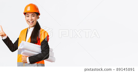 Smiling confident asian female engineer, construction manager in safety helmet, carry blueprints, showing two fingers, ensure building finished in time, standing white background upbeat 89145891
