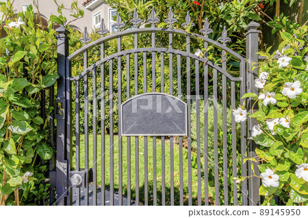 Black wrought iron gate with address number sign and doorbell on the side 89145950