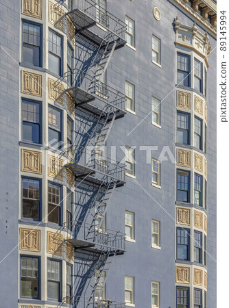 Apartment building exterior with gray wall and metal emergency stairs outdoors 89145994