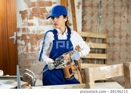 Female builder confidently holding pneumatic jackhammer in house under construction Female builder confidently holding pneumatic jackhammer in house under construction 89146215
