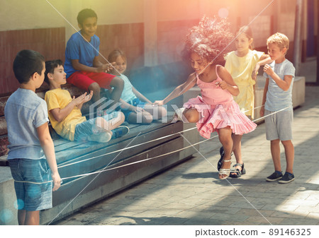 Peruvian little girl jumping game by rubber band with european friends 89146325
