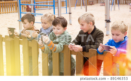 Children with phones near wooden fence 89146353