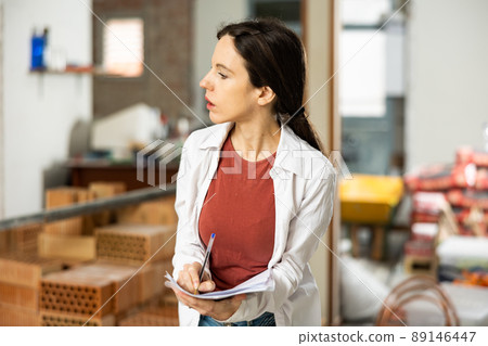 Female designer with papers working in apartment under renovation Female designer with papers working in apartment under renovation 89146447