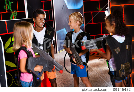 Joyful teens aiming laser guns at other players during lasertag game in dark room Joyful teens aiming laser guns at other players during lasertag game in dark room 89146482