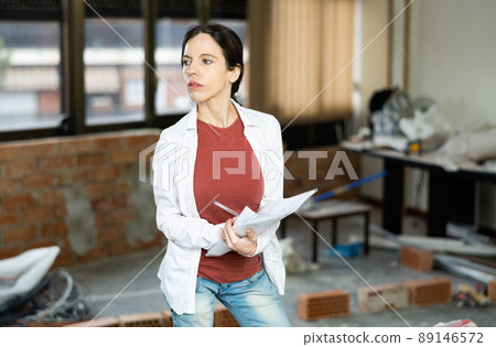 Interested brunette making notes while planning home renovation Interested brunette making notes while planning home renovation 89146572