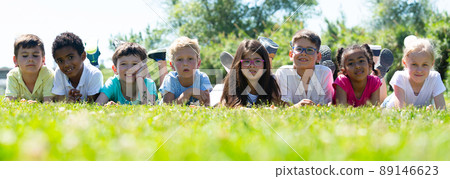 Happy children resting on grass and smiling together in park 89146623