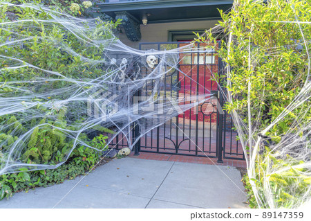 House entrance with fake webs and skeletons at the front of the iron gate in San Francisco, CA 89147359
