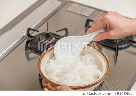 [Middle housewife stirs freshly cooked rice in a clay pot] 89148402