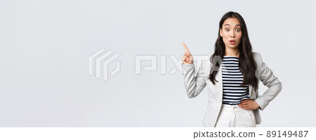 Business, finance and employment, female successful entrepreneurs concept. Surprised and intrigued asian woman working in office hear about interesting promo and pointing left curious 89149487