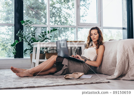 Businesswoman entrepreneur working on laptop from home office space sitting on floor 89150659