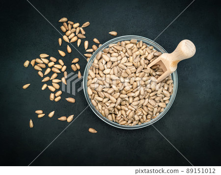 Peeled sunflower seeds in a glass bowl with a small wooden spoon on the black background. Close-up Peeled sunflower seeds in a glass bowl with a small wooden spoon on the black background. Close-up 89151012
