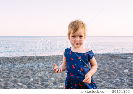 Little cute child girl playing on the seashore in summer 89151503