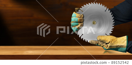 Gloved Hands Holding a Metal Circular Saw Blade on a Wooden Workbench 89152542