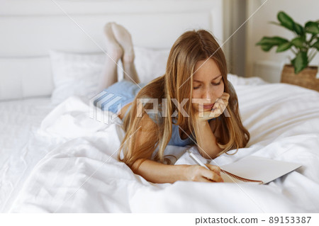 Mental health care, positive thinking and wellness concept. Woman lying in bed, practicing stress relief challenge with journal about feeling and gratitude list, focus on word mental. 89153387