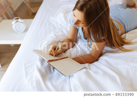 Mental health care, positive thinking and wellness concept. Woman lying in bed, practicing stress relief challenge with journal about feeling and gratitude list, focus on word mental. 89153390