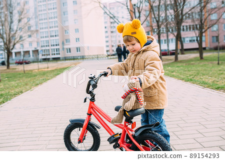 A small child learns to ride a bike for the first time in the city in spring 89154293