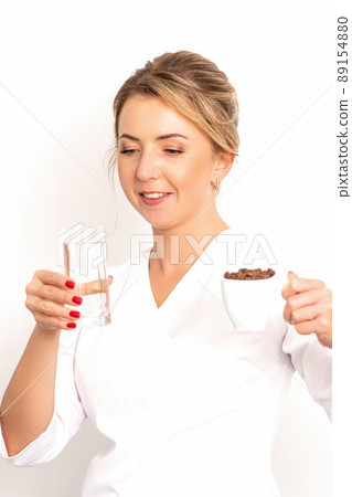 Coffee with water. The female nutritionist holds a cup of coffee beans and a glass of water in her hands on white background 89154880