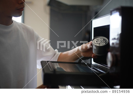 A man trying to heat a can in the microwave A man trying to heat a can in the microwave 89154936