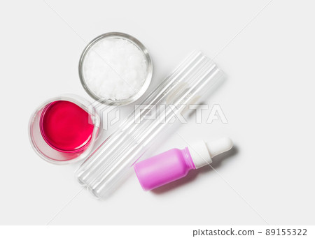 Test tube and serum bottle with dropper placed next to Potassium Permanganate liquid in beaker and microcrystalline wax in glass container. Chemicals for beauty care on white laboratory table. 89155322