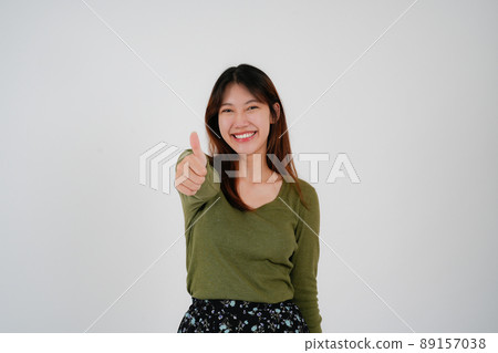 Young asian woman standing over isolated white background happy face smile looking at the camera. Positive person. 89157038