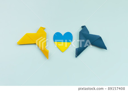 two doves made of origami paper and handmade heart in yellow and blue, in colors of Ukrainian flag on background two doves made of origami paper and handmade heart in yellow and blue, in colors of Ukrainian flag on background 89157408