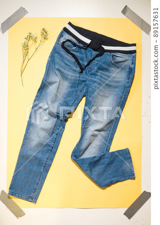blue women's jeans lie on yellow background blue women's jeans lie on yellow background 89157631