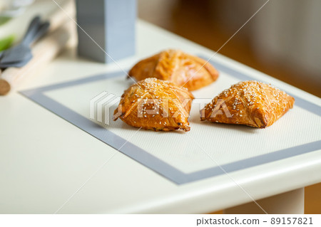 Fresh samsa on a baking mat on the kitchen table Fresh samsa on a baking mat on the kitchen table 89157821