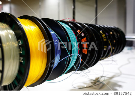 Side view of Colorful plastic PLA and ABS spools with filament for printing on a 3D printer Side view of Colorful plastic PLA and ABS spools with filament for printing on a 3D printer 89157842