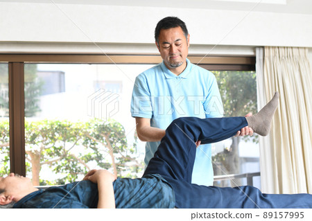 Male chiropractor doing leg manipulative massage 89157995