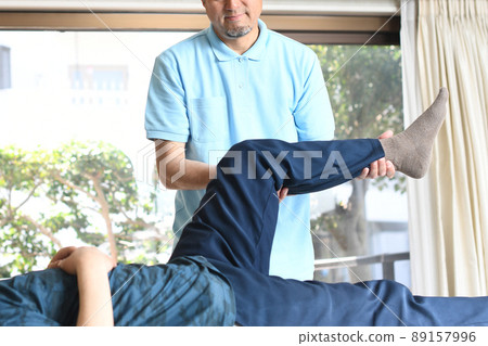 Male chiropractor doing leg manipulative massage Male chiropractor doing leg manipulative massage 89157996