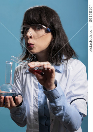 Biochemist specialist having professional chemistry glass jars while carefully mixing unknown compounds. Laboratory worker expert mixing liquid substances while working on chemical experiment. 89158194