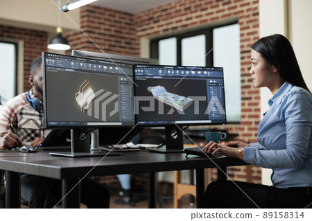 Creative agency professional employee creating 3D sketch using advanced software. Digital engineer developing prototype mesh using modern computer while sitting at desk in office. Creative agency professional employee creating 3D sketch using advanced software. Digital engineer developing prototype mesh using modern computer while sitting at desk in office. 89158314